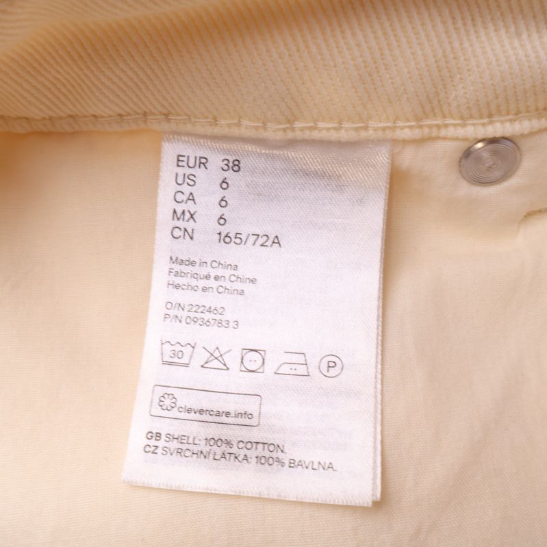 Materialetikett av krämfärgade jeans, 100% bomull
