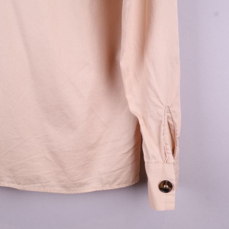 Beige skjorta ärm med knappdetalj