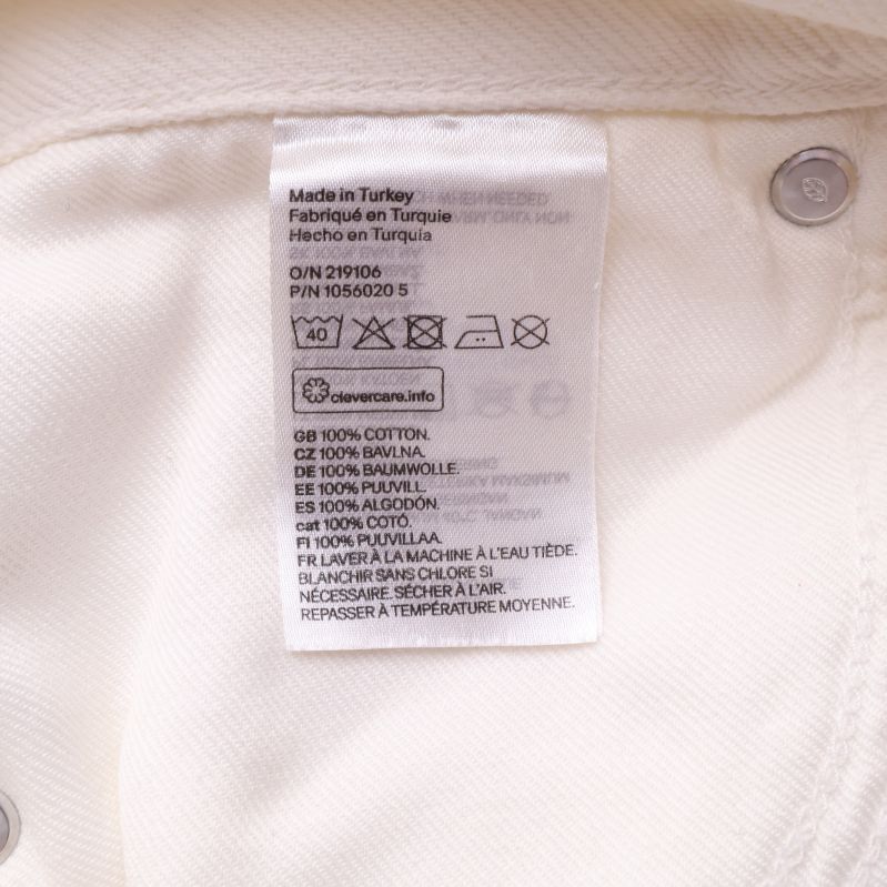 Materialetikett i jeans, visar 100% bomull