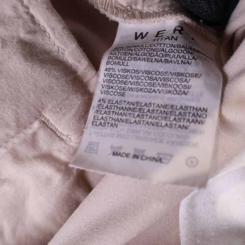 Materialetikett inuti beige byxor
