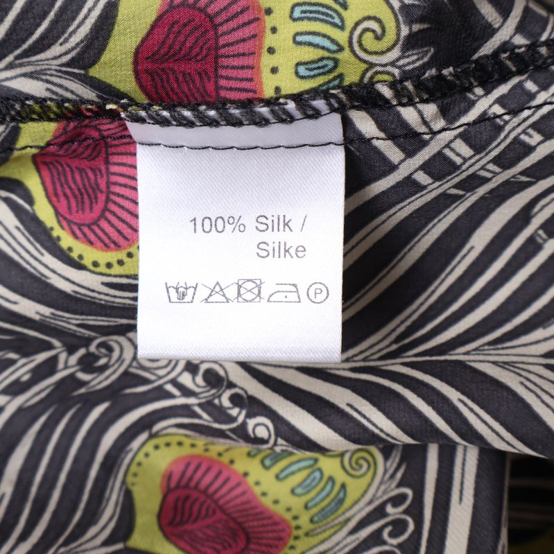 Materialetikett som visar 100% silke