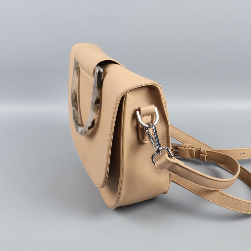 Närbild av handtag på beige väska