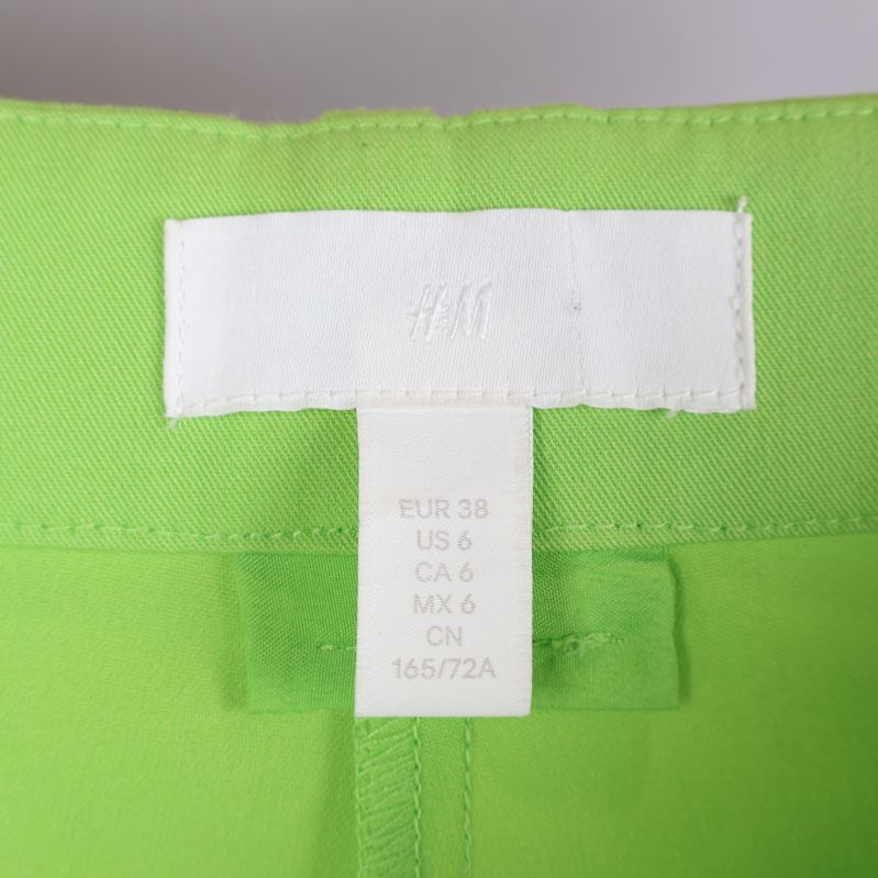 Märkeslabel av H&M på gröna byxor