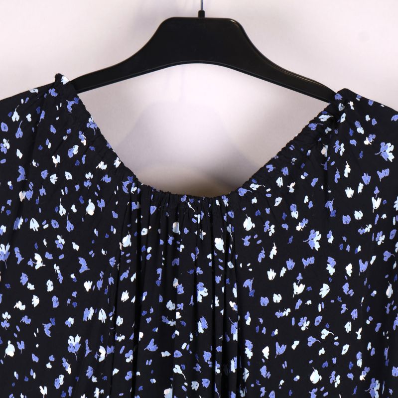 Bakifrån detalj av klänningshals mot mönstrad bakgrund