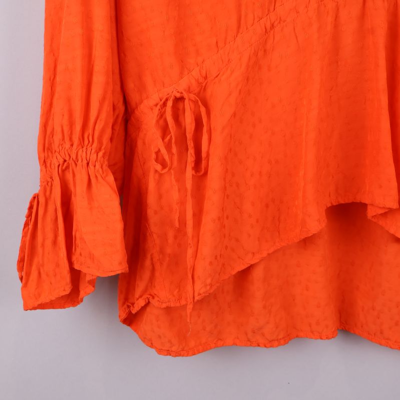 Ärmdetaljer med knytband på orange blus