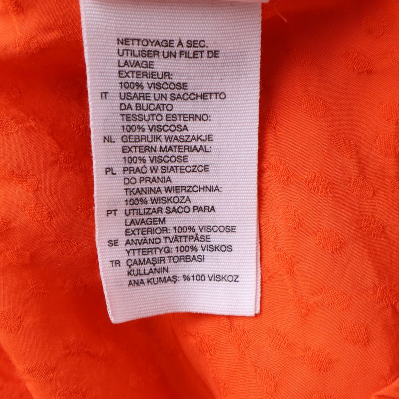 Materialetikett visar 100% viskos på orange blus