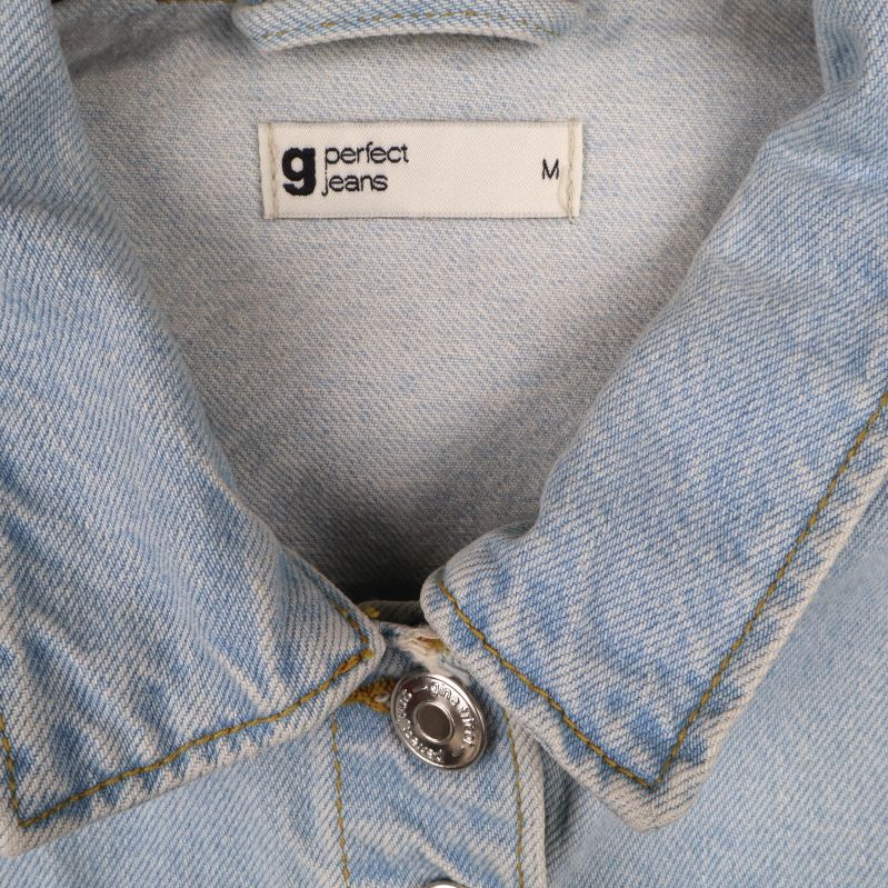 Närbild av etikett med jeansjackas märke och storlek