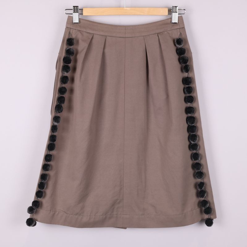 Baksida av brun kjol med pom-poms