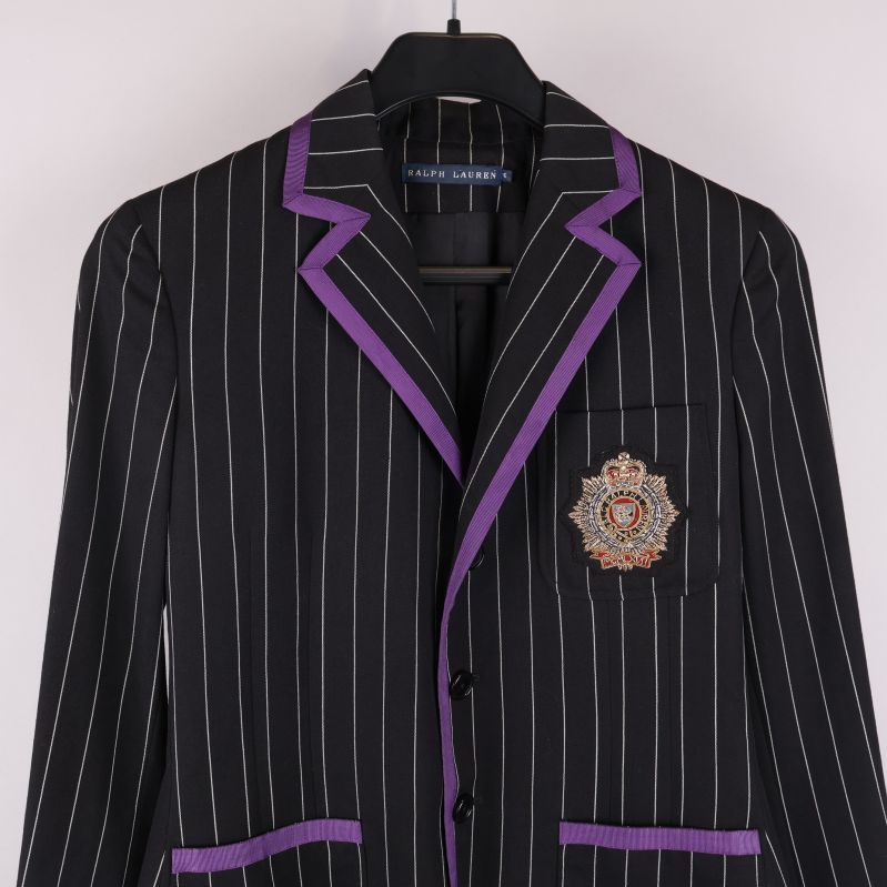 Närbild av kavajens insignia på bröstfickan