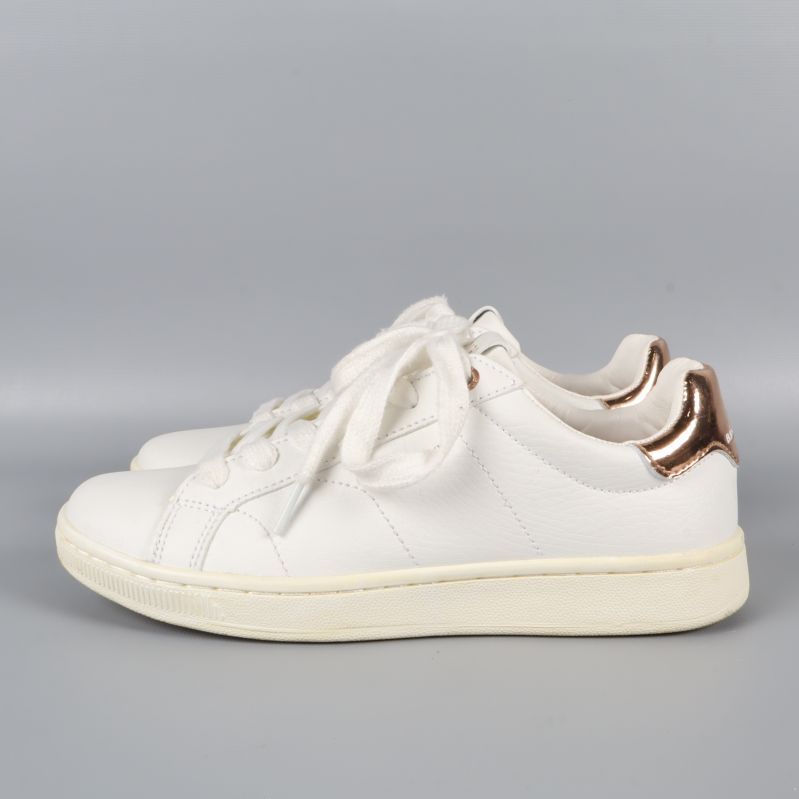 Sida av sneakers med kopparfärgade detaljer