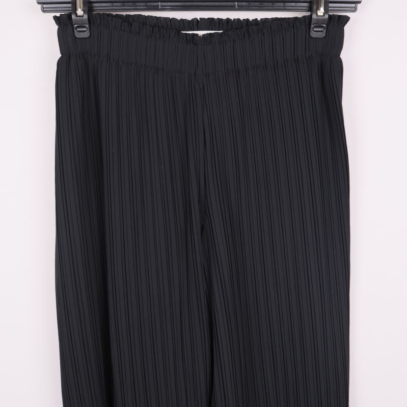 Närbild på övre delen av plisserade byxor