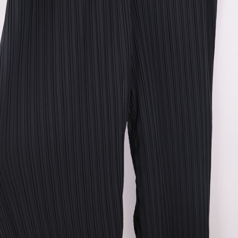 Närbild på tyg och plisserade detaljer på byxorna