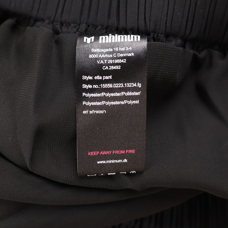 Materiallapp med information om polyester på svarta byxor