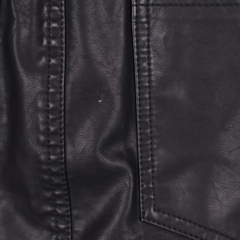 Närbild på söm och bakficka i svart skinnimitation