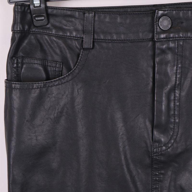 Närbild på fickdetaljer och sömmar på svart skinnimitationskjol