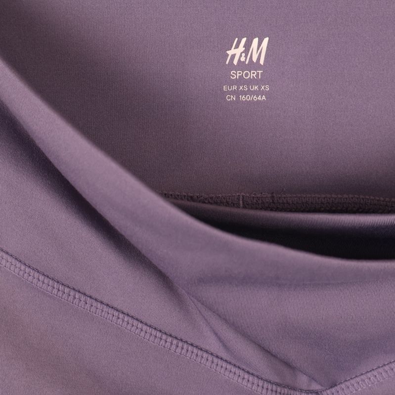 Närbild på invändig H&M Sport-logotyp i lila material