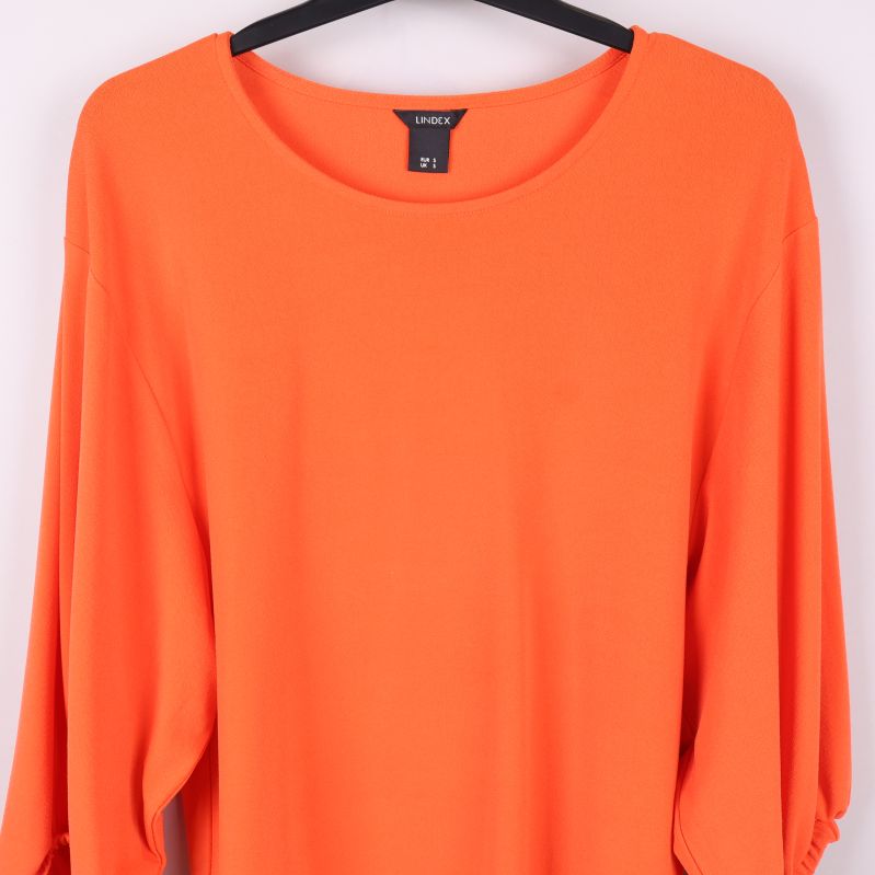 Detalj av rund hals och ärmar med resår på orange topp