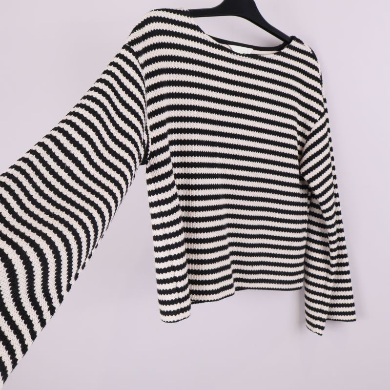 Stickad tröja med vid ärm i fokus och randigt mönster