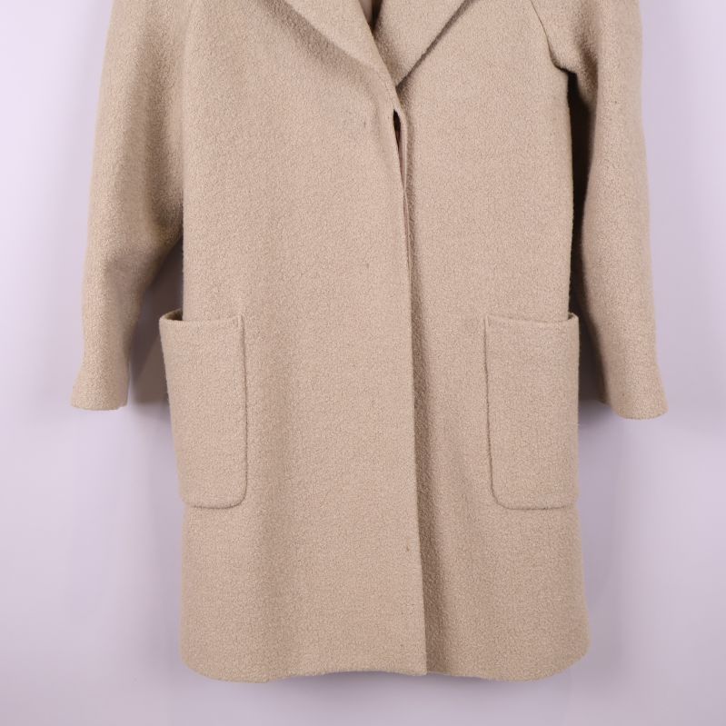 Närbild av stora patchfickor på beige kappa