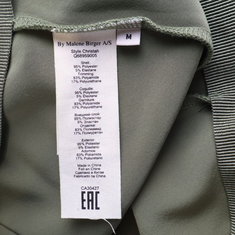 Materialetikett som visar materialinnehåll på gröna byxor