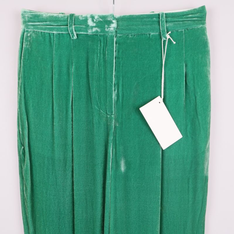 Närbild på midjedetaljer samt hällor och etikett på gröna sammetsbyxor