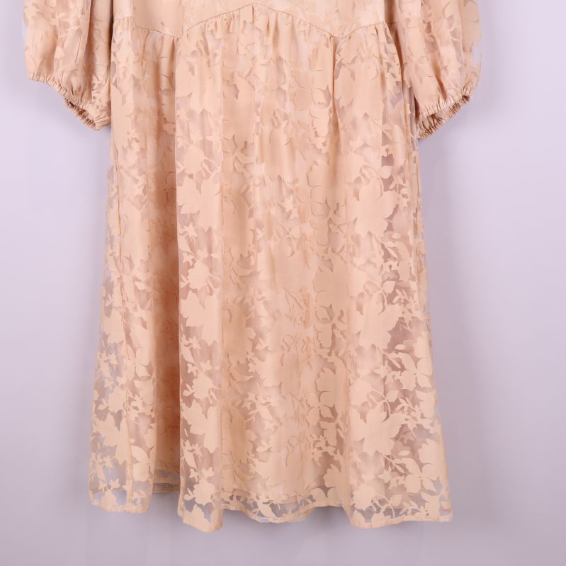 Nederdel av beige klänning med transparent blommigt tyg och fåll