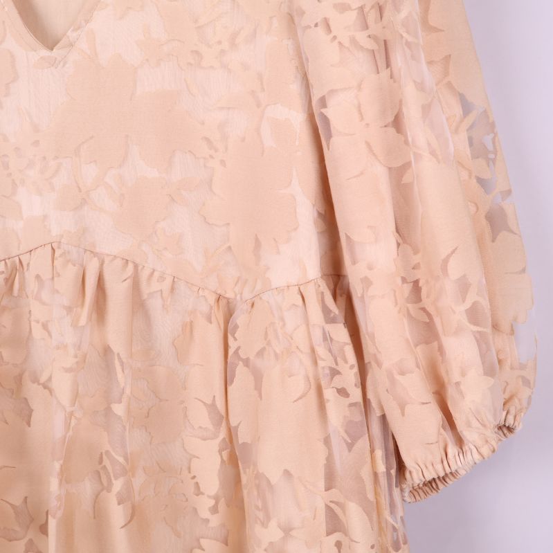 Närbild på puffärm med resår i beige blommigt tyg