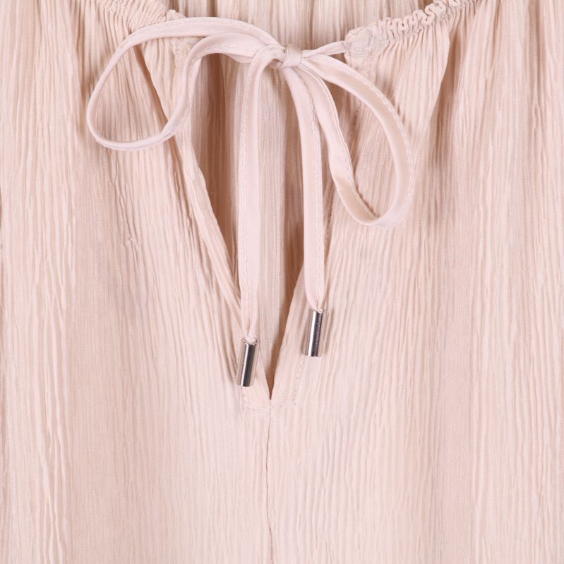 Detalj av knytband med metalländar på ljusbeige blus