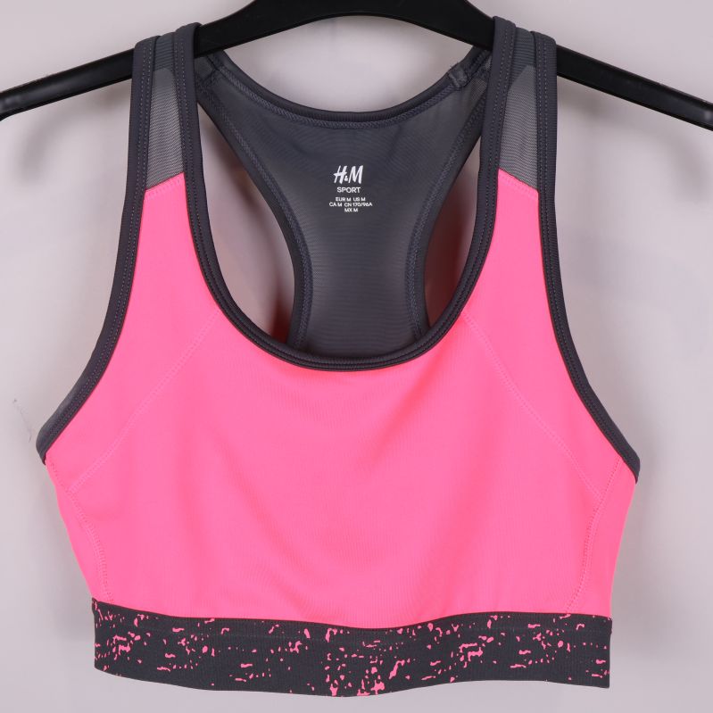 Sport-bh framifrån med rosa och svart design på galge