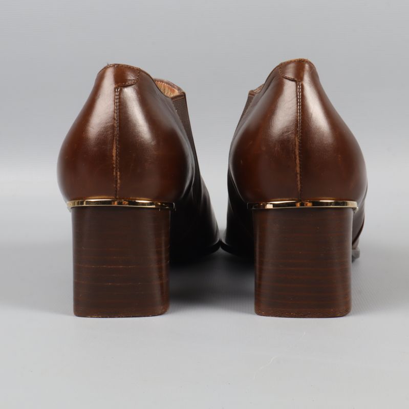 Baksidan på bruna klackskor med gulddetalj på klacken