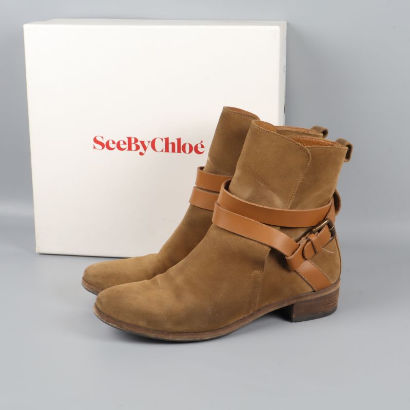 Bruna boots med remmar framför originalförpackning
