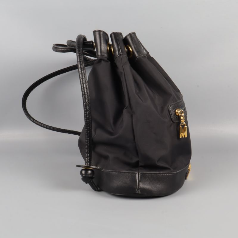 Ryggsäckens sida visar justerbara axelremmar och metallmärke