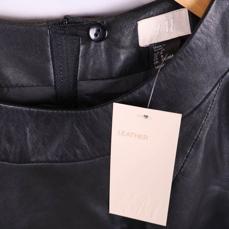 Närbild på krage med H&M-lapp och märkning LEATHER