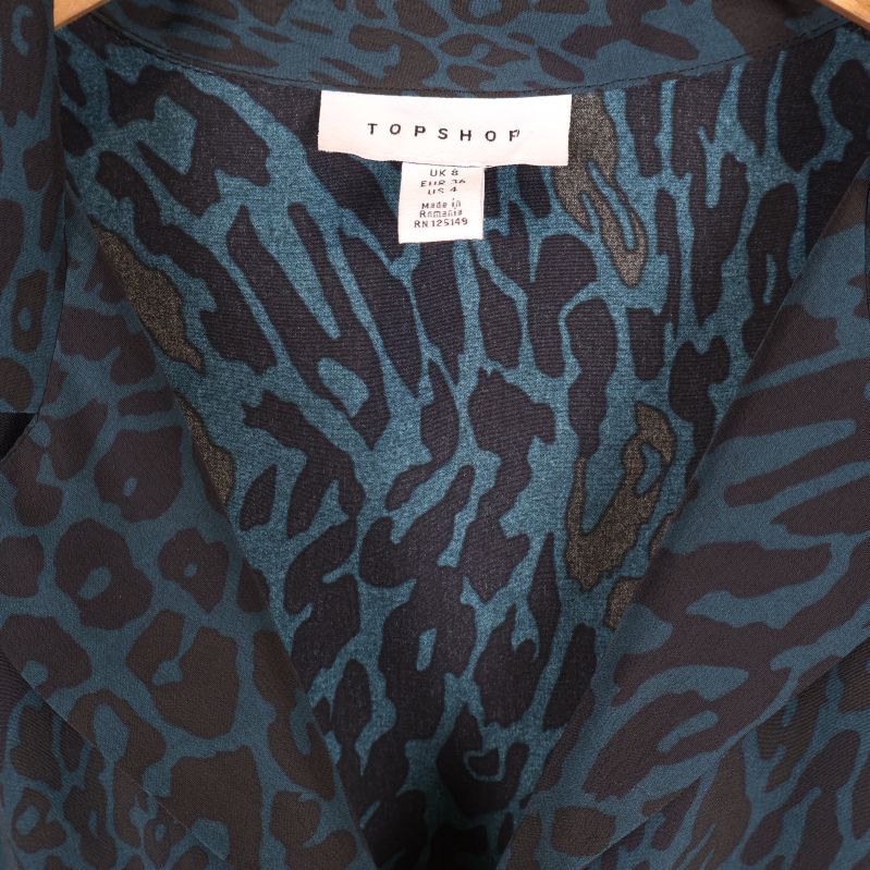 Närbild på krage och etikett med TOPSHOP-logga i klänningen