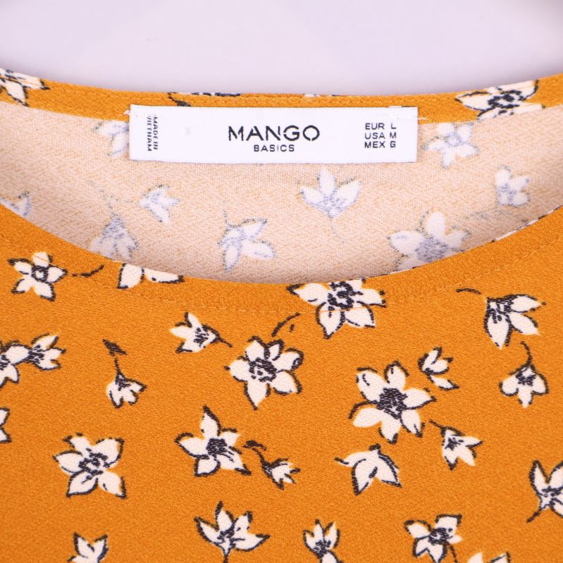 Närbild av etikett med Mango-logo i halsen