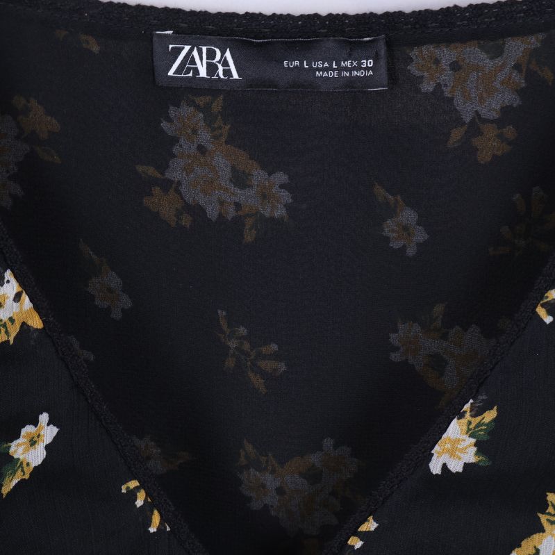 Närbild på ZARA-etikett i blommig svart blus