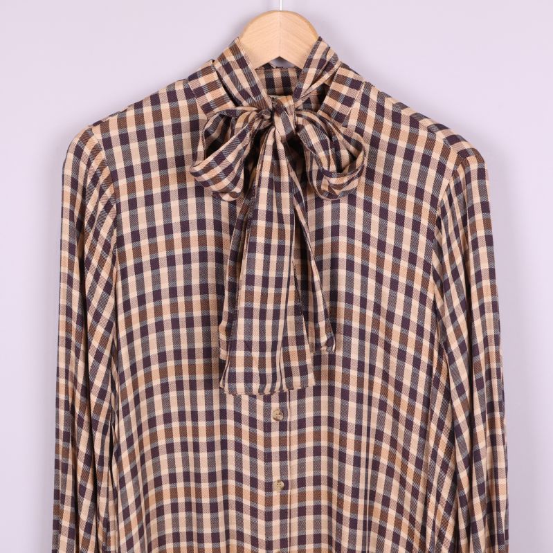 Närbild på knytband vid halsen och rutigt mönster