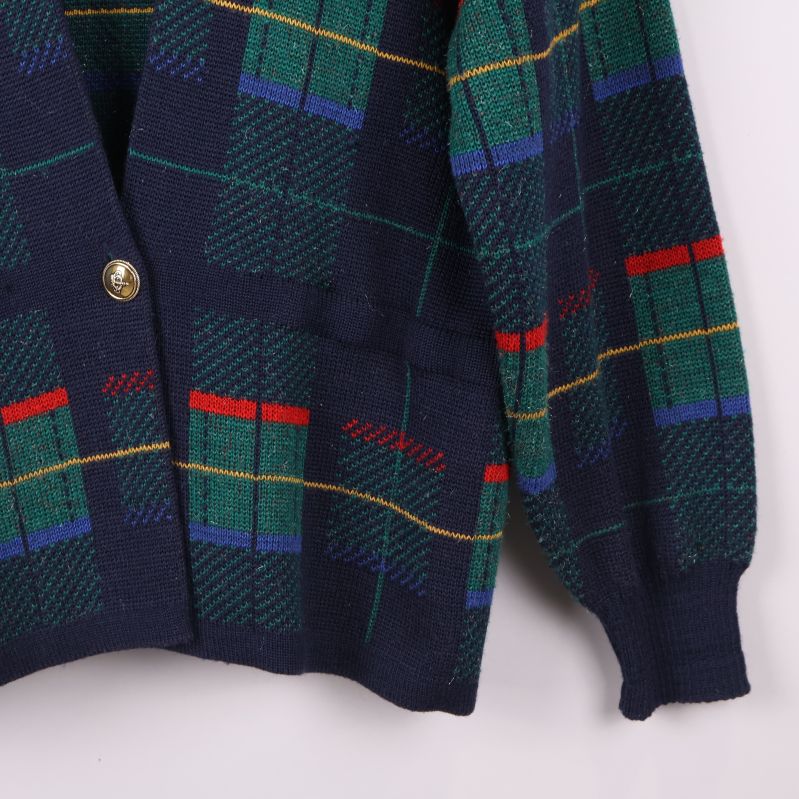 Närbild på nederdelen av koftan med knapp och rutigt mönster