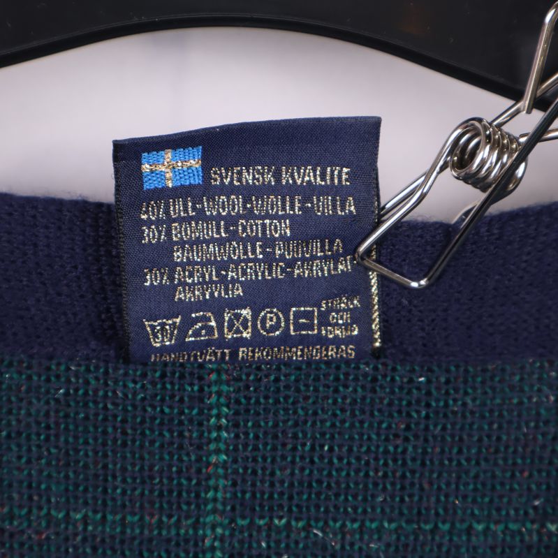 Materialetikett som visar sammansättning i ull, bomull och akryl