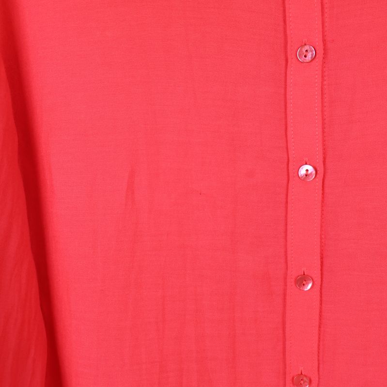 Närbild på tyg och knappar på röd skjorta