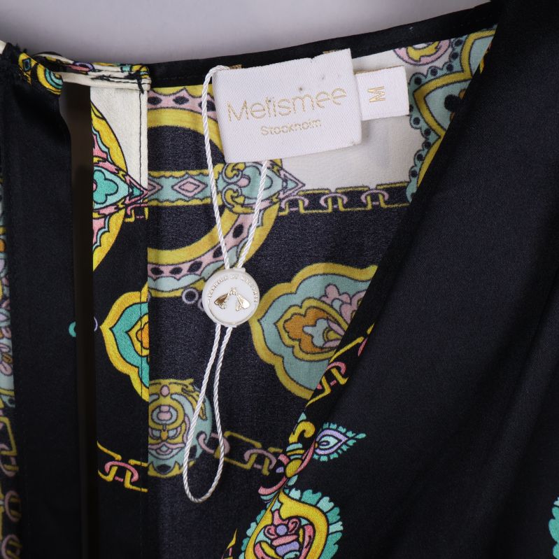 Närbild på halsringning och etikett från Melismee Stockholm