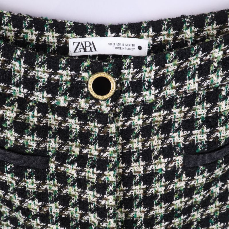 Närbild på hundtandsmönster och midjedetaljer med guldknapp