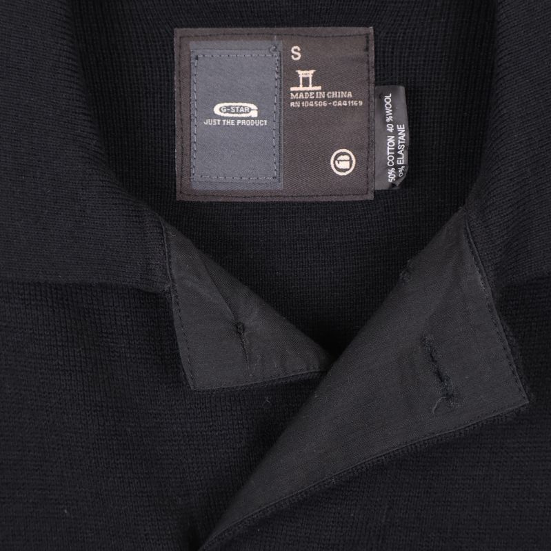 Närbild på etikett och krage av svart kofta