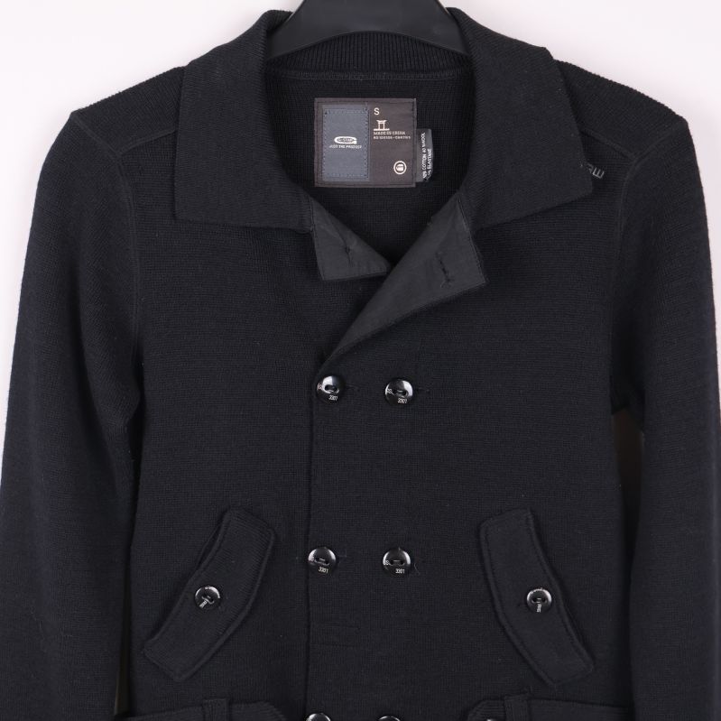 Övre delen av svart kofta med knappar och fickor