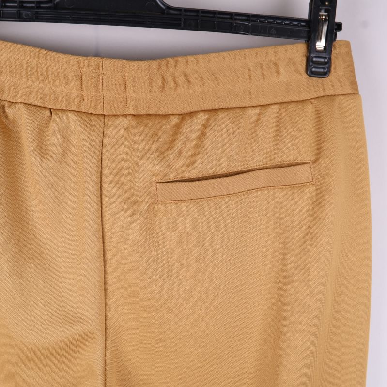 Närbild på bakficka med resår och slät finish i beige tyg