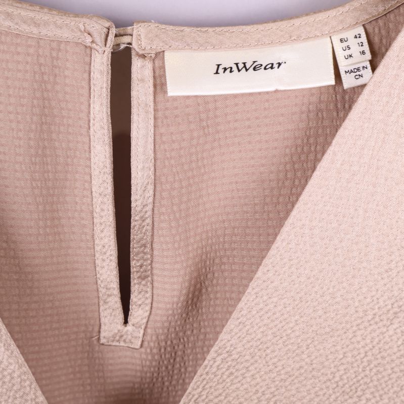 Närbild på v-ringning och märkning InWear i blus