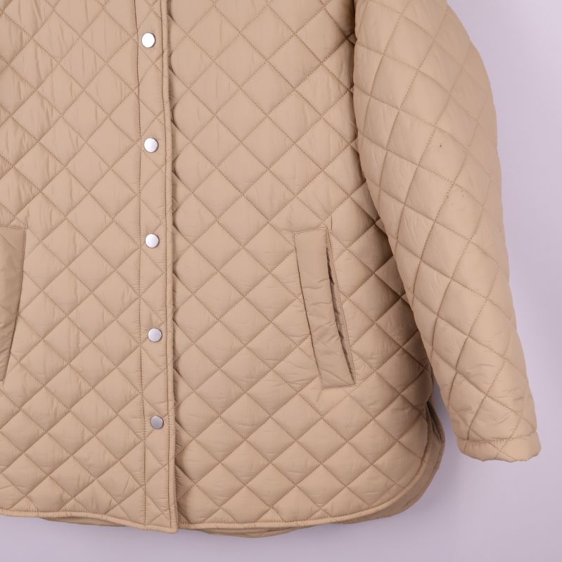 Höger ficka och nederdel av beige quiltad jacka