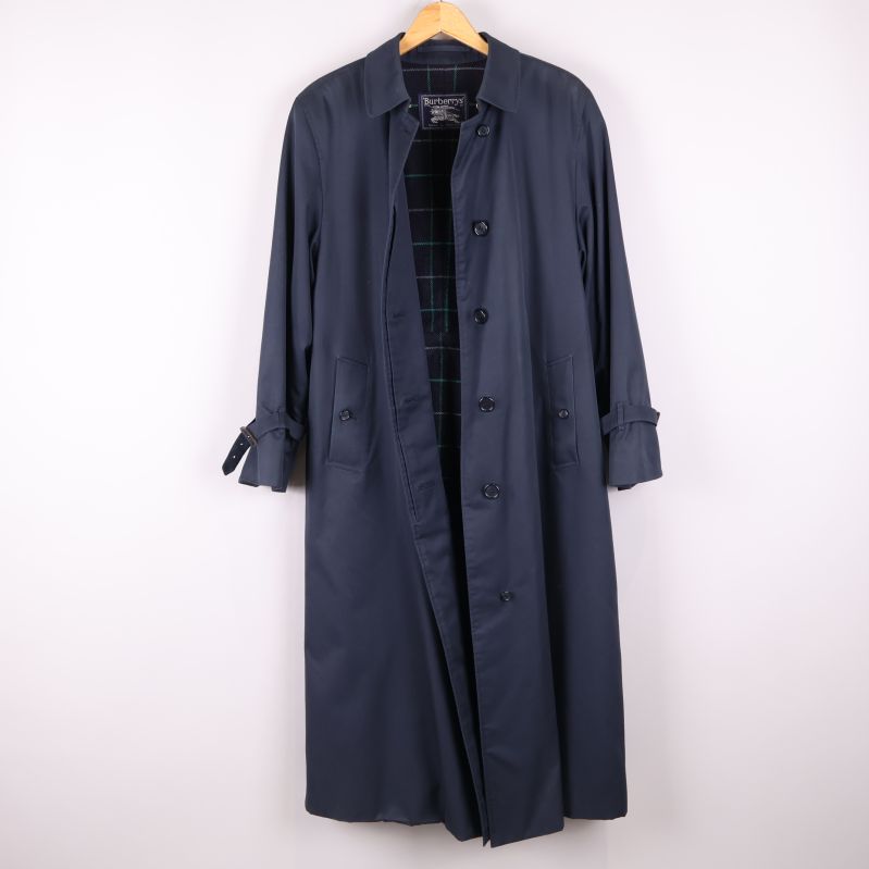 Lång mörkblå trenchcoat öppen med rutigt foder synligt