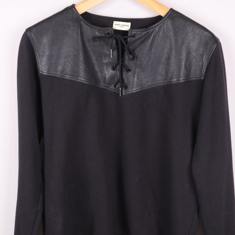 Närbild på överdelen av sweatshirten med läder och snörning