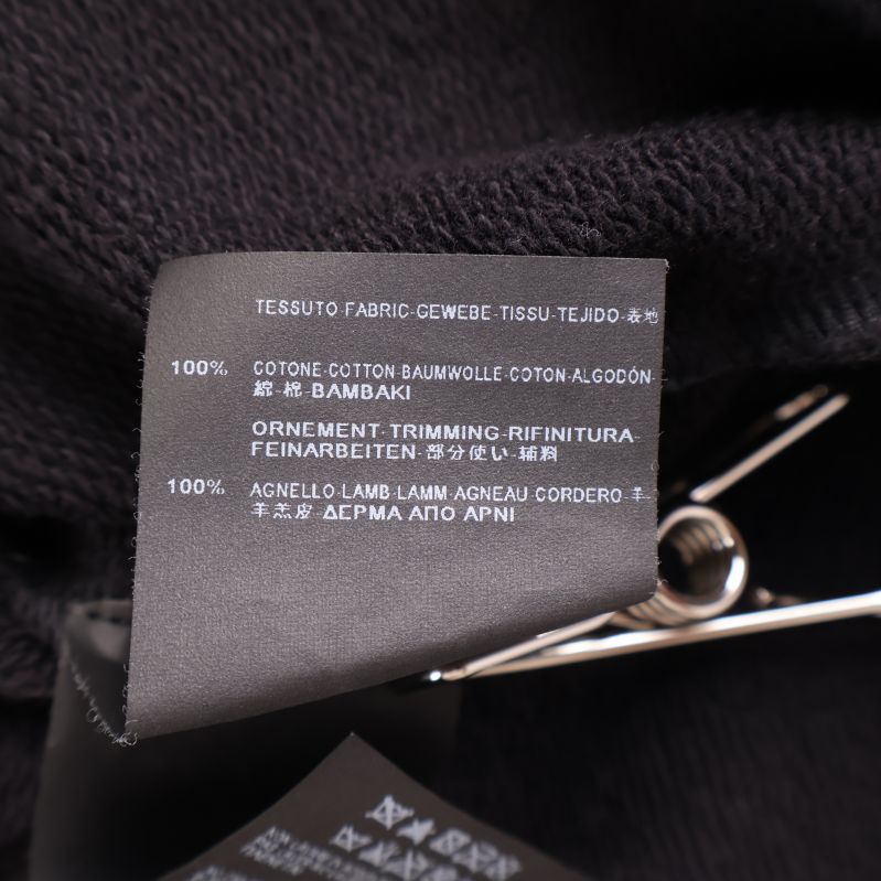 Materialetikett som visar 100% bomull och 100% lammnappa